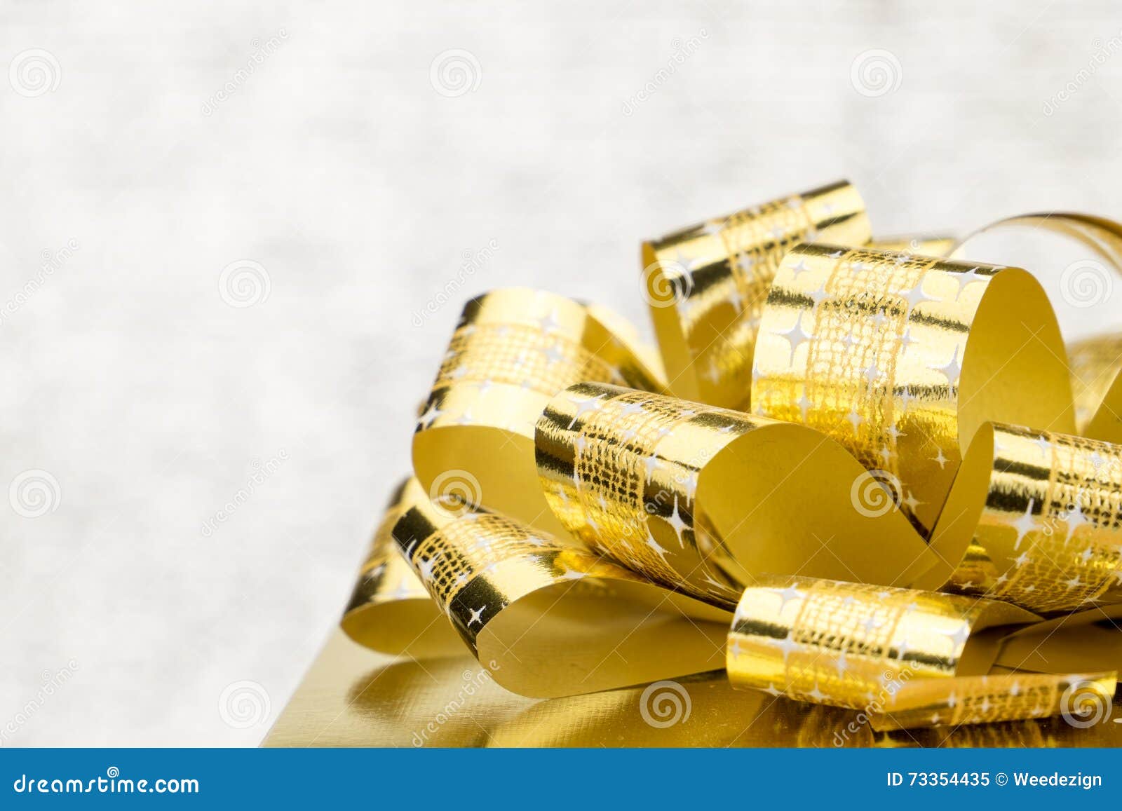 close up golden present box with big bow at bokeh white blur background